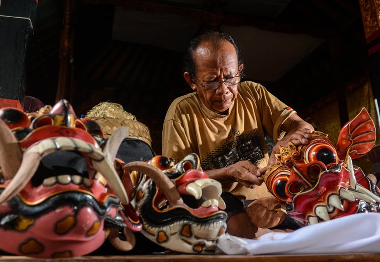 Un homme en train de fabriquer des masques colorés